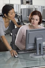 Office workers conferring at computer.