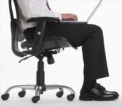 Seated businessman using laptop computer.