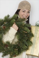 Woman holding holiday wreath and present.