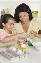 Mother and daughter coloring Easter eggs.