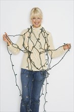Woman tangled up in holiday lights.