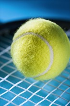 Closeup of tennis racquet and ball.