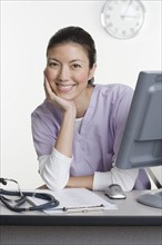 Female healthcare worker leaning on desk.