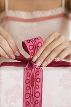 Woman tying ribbon on gift.