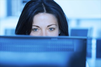 Woman in office looking at computer screen.