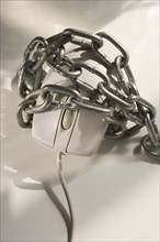 Closeup of computer mouse covered in chains.