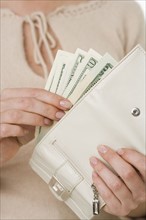 Woman putting cash in wallet.