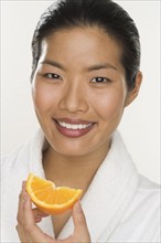 Portrait of a woman eating orange slice.