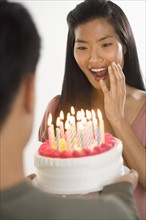 Woman presented with surprise birthday cake.