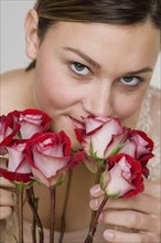 Close up of woman smelling stemmed roses.