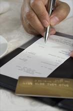 Close up of man signing credit card receipt at restaurant.