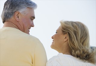 Senior couple smiling and looking at each other outdoors.