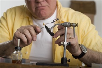 Senior man using soldering iron.