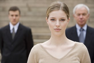 Portrait of woman with businessmen in background.