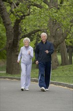 Senior couple powerwalking in park.