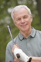 Portrait of senior man with golf club.