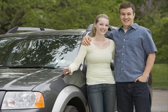 Couple standing with new car.