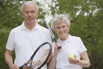 Portrait of mature couple with tennis racquets.