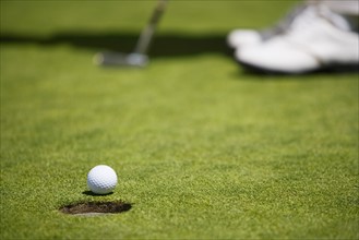 Low angle view of golf ball rolling towards cup .