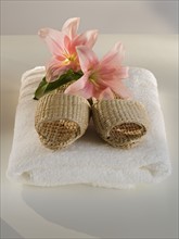 Straw sandals and flowers on folded towel.