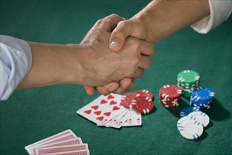 Two men shaking hands over poker game.