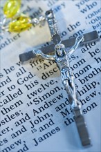 Close up of crucifix with rosary on Bible.