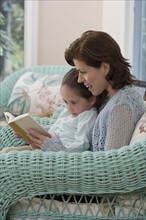 Mother reading to young daughter .