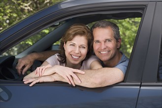 Couple smiling and sitting in car.