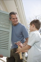 Father and young son fixing shutters.