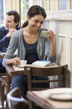 Woman looking at digital camera in restaurant.