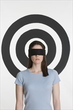 Blindfolded woman standing in front of bull’s eye.