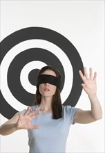 Blindfolded woman standing in front of bull’s eye.
