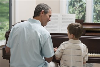 Father and young son playing piano.