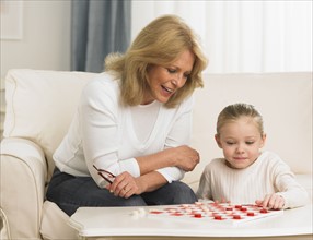 Grandmother and young granddaughter playing checkers.