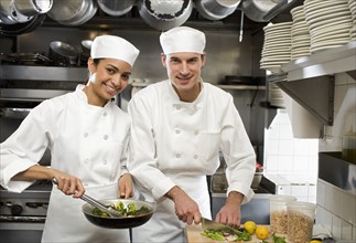 Male and female chefs in restaurant kitchen.