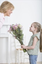 Young granddaughter giving grandmother bouquet of flowers.