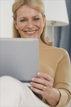 Senior woman using laptop on sofa.