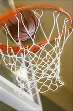 Close up of basketball entering hoop.