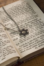 Star of David necklace on book with Hebrew text.