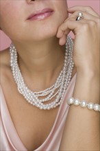 Close up of woman wearing pearls.