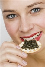 Close up of woman eating caviar on a cracker.