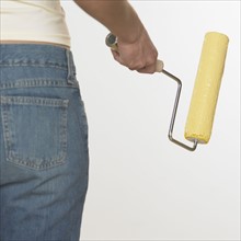 Rearview of woman holding paint roller.