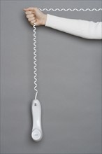 Telephone dangling by cord.