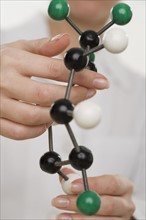 Hands holding molecular model.