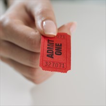 Close up studio shot of woman's hand holding ticket.