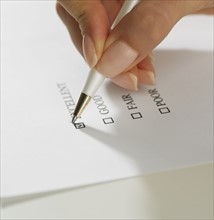 Close up of woman's hand marking check box with pen.