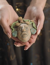 Close up of woman's hands holding clay face.