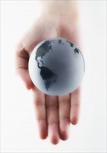 Hand holding a miniature globe.