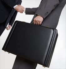 Businessman with briefcase shaking hands.