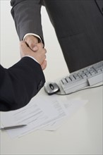 Businessmen shaking hands over computer.